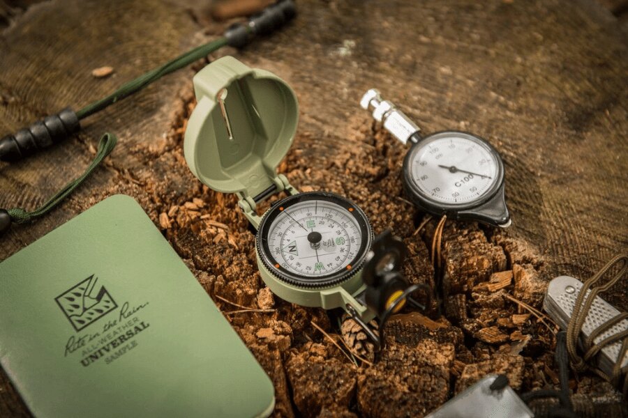 Kompas Ranger MK2 Helikon-Tex® a odolný zápisník na pařezu pro orientaci v přírodě. Foto: Helikon-Tex, Rigad