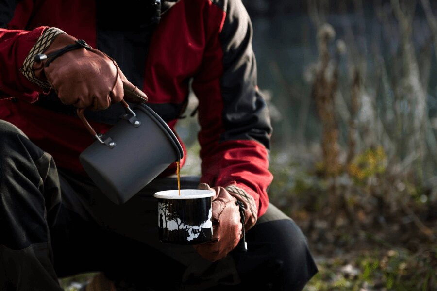 Příprava horkého nápoje z trekového ešusu do smaltovaného hrnku při podzimním bivaku. Foto: Rigad