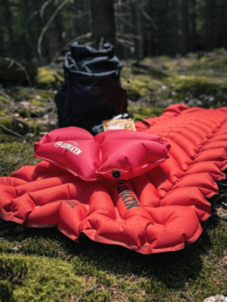 Nafukovací karimatka a batoh připravené k nocování v lesním tábořišti. Foto: Rigad