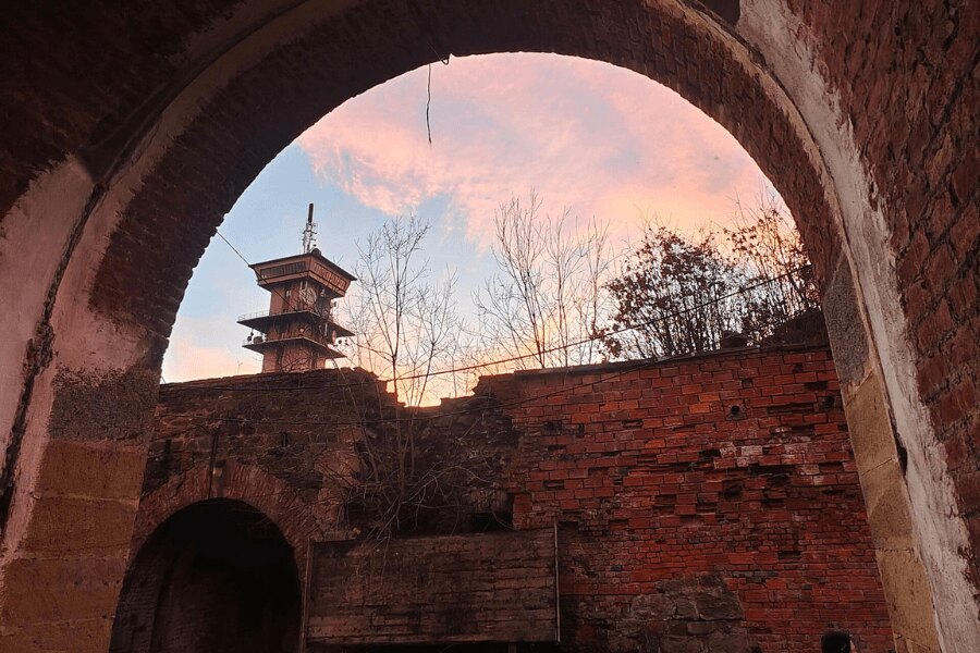 Fort Radíkov u Olomouce, pohled skrz cihlový oblouk na pevnostní areál a vyhlídkovou věž. Foto: https://commons.wikimedia.org/wiki/File:Pohled_od_vstupu_do_Fortu_Radíkov_na_nedalekou_věž.jpg