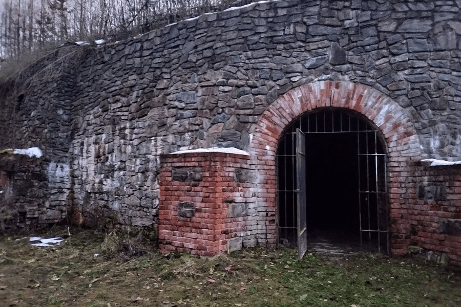 Vstup do Fortu Radíkov, kamenná pevnostní zeď a zabezpečený vchod do podzemních prostor. Foto: https://commons.wikimedia.org/wiki/File:Fort_Radíkov_04.jpg