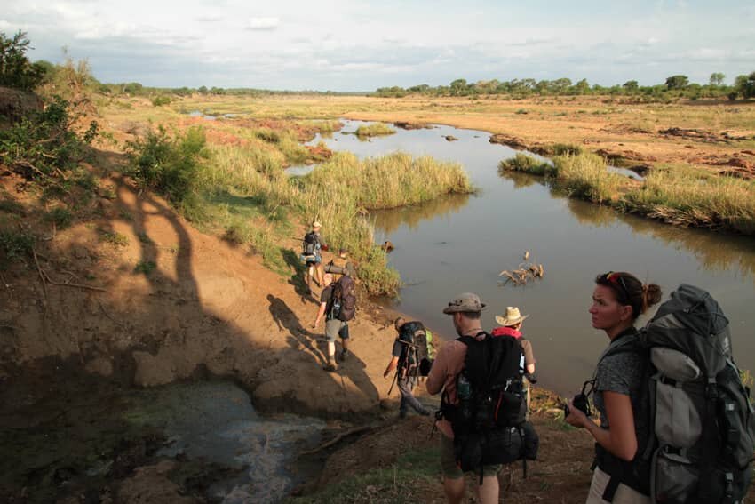 Lidé kráčející za sebou v africké přírodě